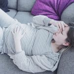 Young pregnant woman suffering pain at home